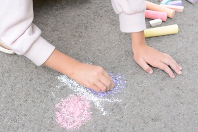 Photo of Little child drawing butterfly with chalk on asphalt, closeup