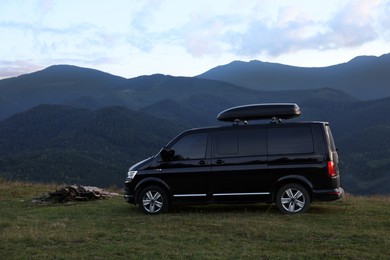 Black van parked in clearing among mountains