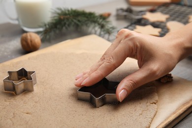 Photo of Woman making gingerbread star with cutter at table, closeup. Homemade Christmas biscuits
