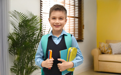 Little boy in uniform with school stationery at home