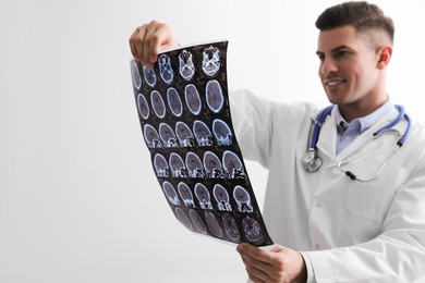 Doctor examining MRI images of patient with multiple sclerosis in clinic, space for text