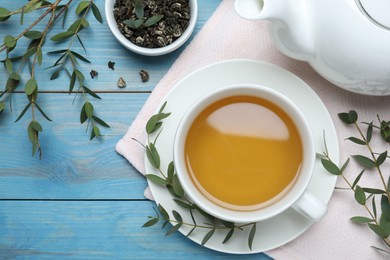 Aromatic eucalyptus tea on light blue wooden table, flat lay