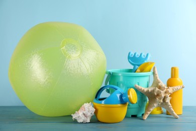 Beach ball and sand toys on light blue wooden table