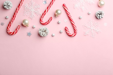 Flat lay composition with candy canes and Christmas decor on pink background. Space for text