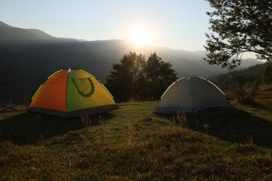Two color camping tents on hill in mountains