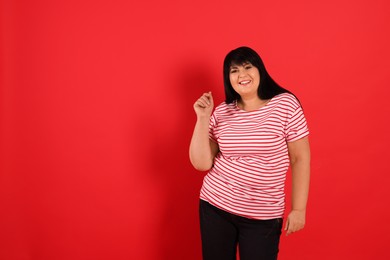 Beautiful overweight mature woman on red background. Space for text