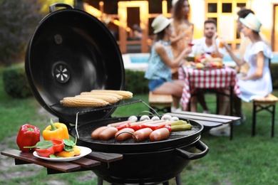 Photo of Barbecue grill with sausages and vegetables outdoors