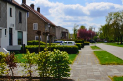 Photo of Blurred view of suburban street with beautiful houses and green shrubbery