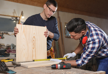 Professional carpenters working with wooden boards in workshop