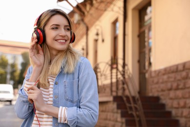 Happy young woman with headphones listening to music on city street