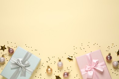 Photo of Beautiful gift boxes, Christmas balls and golden confetti on beige background, flat lay. Space for text