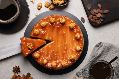 Sliced delicious caramel cheesecake with popcorn served on light grey table, flat lay