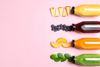 Flat lay composition with bottles of colorful juices and fresh ingredients on pink background. Space for text