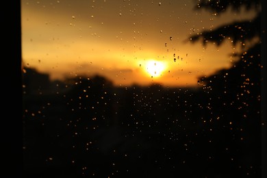 Blurred view of beautiful sunset through window with condensate drops