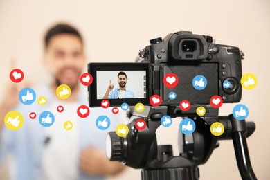 Image of Young blogger shooting video with camera against beige background, focus on screen