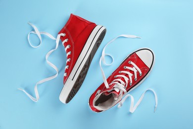 Photo of Pair of trendy sneakers on light blue background, flat lay