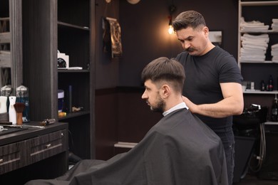 Professional hairdresser making stylish haircut in barbershop, space for text