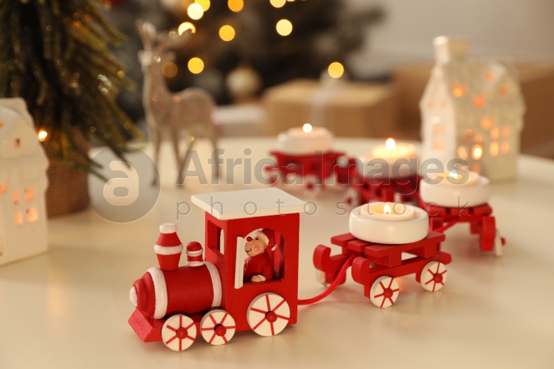 Photo of Red toy train as Christmas candle holder on white table in room