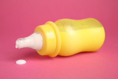 Photo of Feeding bottle with milk on dark pink background