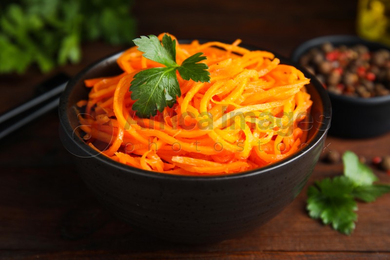 Delicious Korean carrot salad with parsley in bowl on wooden table, closeup