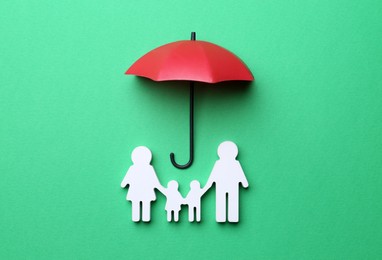 Mini umbrella and family figure on green background, flat lay