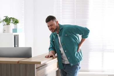Photo of Man suffering from back pain in office. Bad posture problem