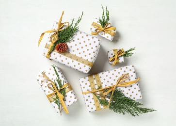 Christmas gift boxes with fir branches on white wooden background, flat lay