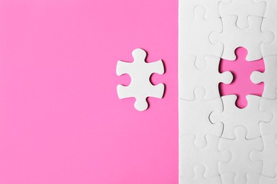 Blank white puzzle with separated piece on pink background, flat lay. Space for text