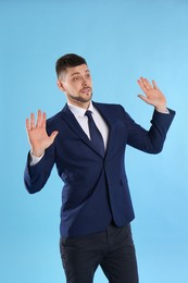 Man in suit avoiding something on light blue background