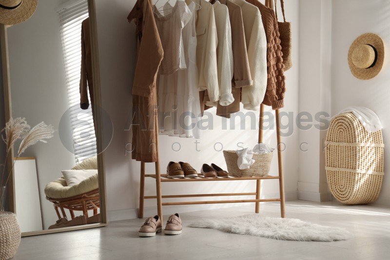 Rack with stylish women's clothes in dressing room. Modern interior design