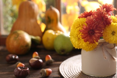 Photo of Beautiful chrysanthemum flowers, chestnuts and acorns on wooden table, space for text. Autumn still life