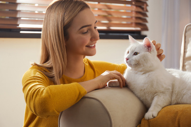 Young woman petting her beautiful white cat at home. Fluffy pet