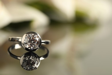 Photo of Beautiful engagement ring against blurred background, closeup. Space for text