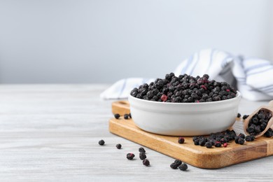 Bowl and scoop with dried blueberries on white wooden table. Space for text
