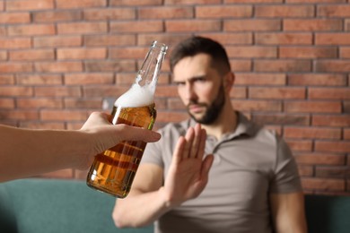 Man refusing to drink beer indoors, closeup. Alcohol addiction treatment