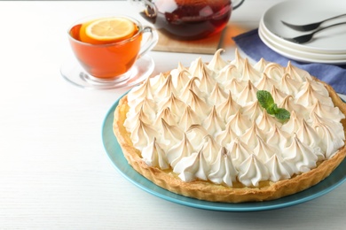 Delicious lemon meringue pie decorated with mint on  white table, space for text