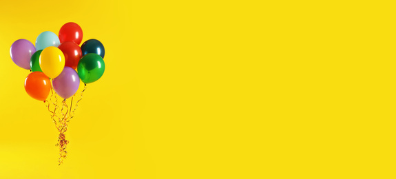 Bunch of bright balloons on yellow background, space for text. Banner design 