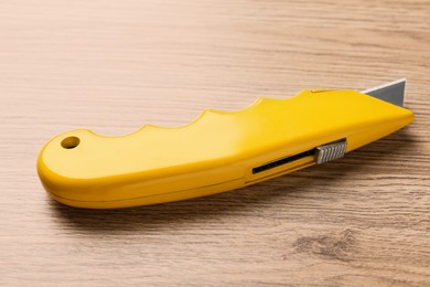 Yellow utility knife on wooden table. Construction tool
