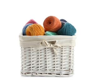 Photo of Wicker basket with clews of colorful knitting threads on white background