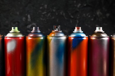 Used cans of spray paint on black marble background