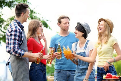 Photo of Young people with bottles of beer outdoors. Summer picnic