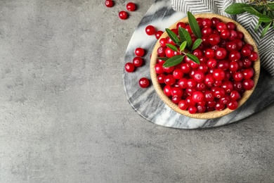 Photo of Tasty ripe cranberries on grey table, flat lay. Space for text