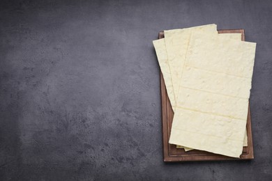 Photo of Delicious Armenian lavash on dark table, top view. Space for text