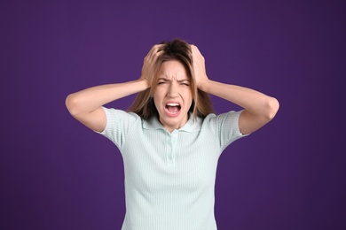 Portrait of stressed young woman on purple background