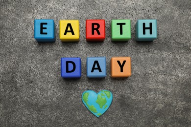 Colorful cubes with words Earth Day and heart shaped plasticine planet on grey table, flat lay