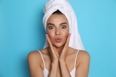 Photo of Beautiful young woman with towel on head against light blue background