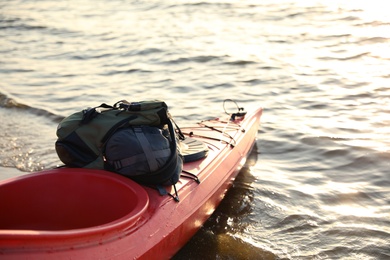 Red kayak with bags on river. Summer camp activity