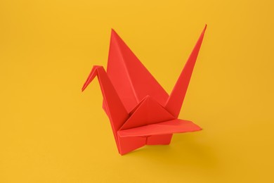 Photo of Origami art. Beautiful red paper crane on orange background