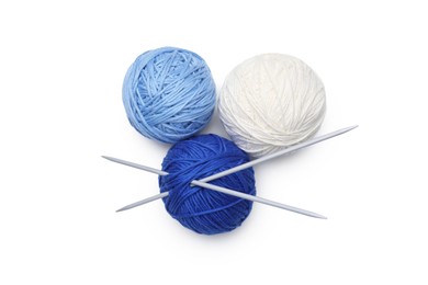 Soft woolen yarns with knitting needles on white background, top view