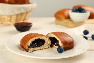 Photo of Delicious baked patty with jam and blueberries on white wooden table